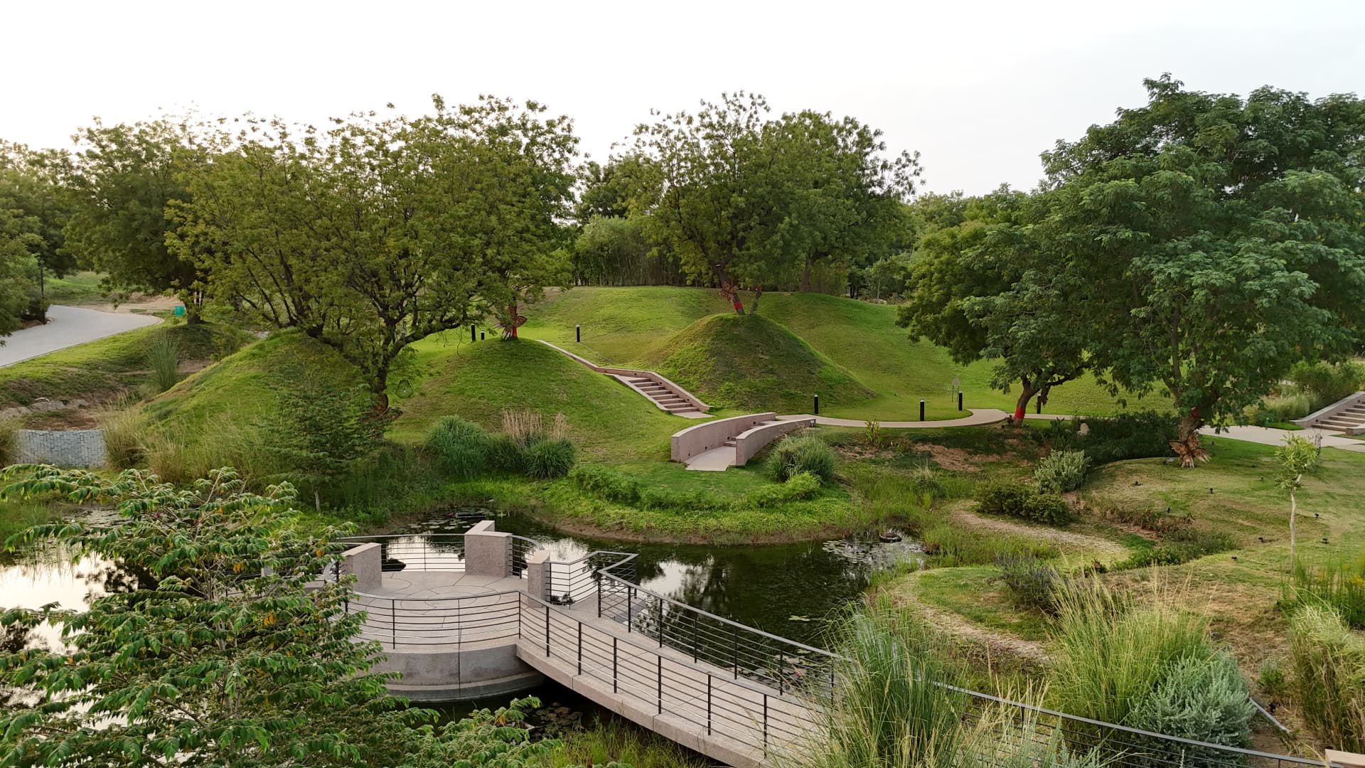 Landscaped green mounds and lakeside boardwalk